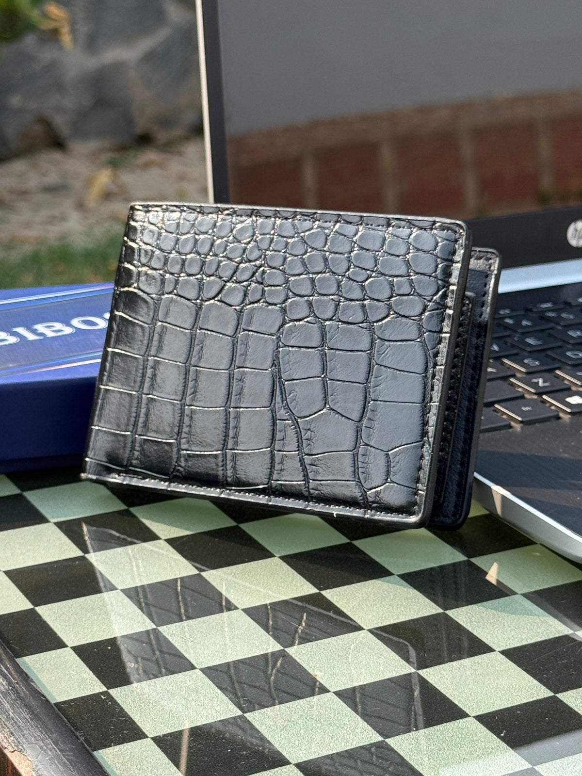 Black crocodile leather bifold wallet on chess board
