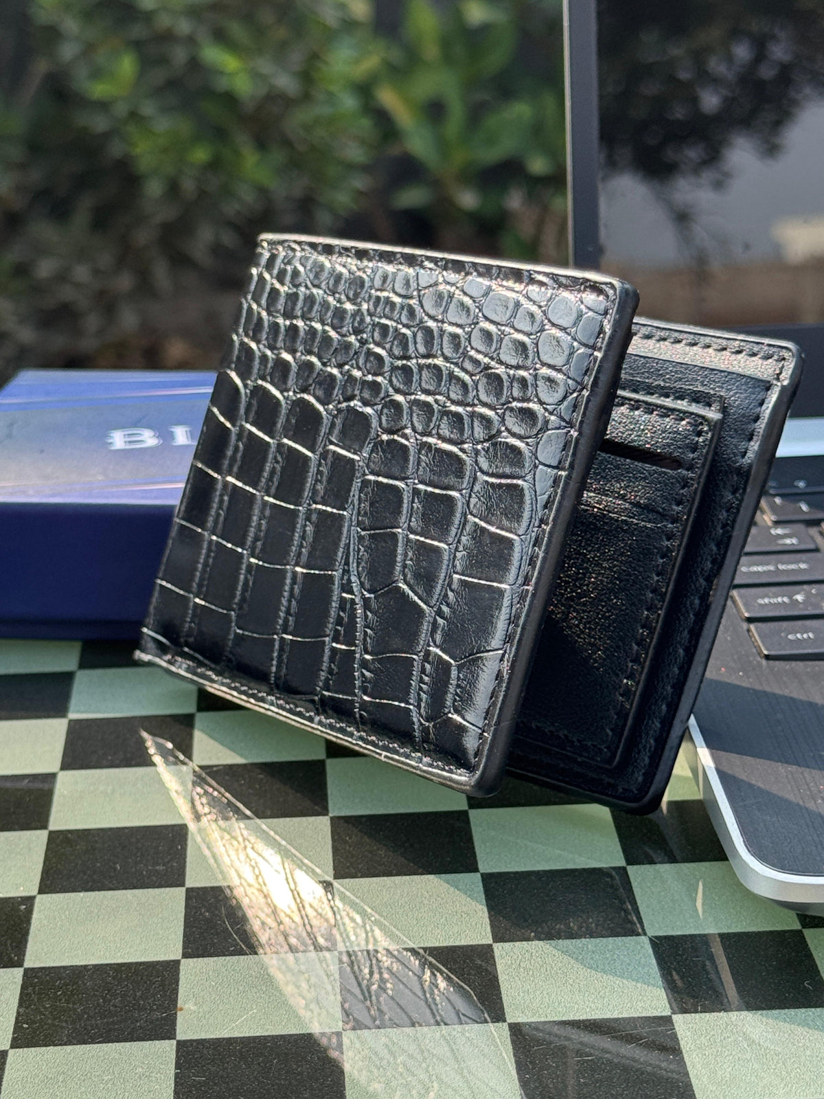 Crocodile embossed black leather bifold wallet held in hand